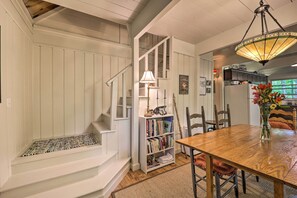 A dining area with a wooden table, chairs, a bookshelf, and a staircase. - Spacious Cabin - 4 Mi to Blue Ridge Parkway! (Boone)