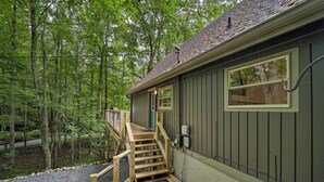 Une cabane dotée d’une terrasse en bois, d’un escalier et offrant une vue sur la forêt environnante.