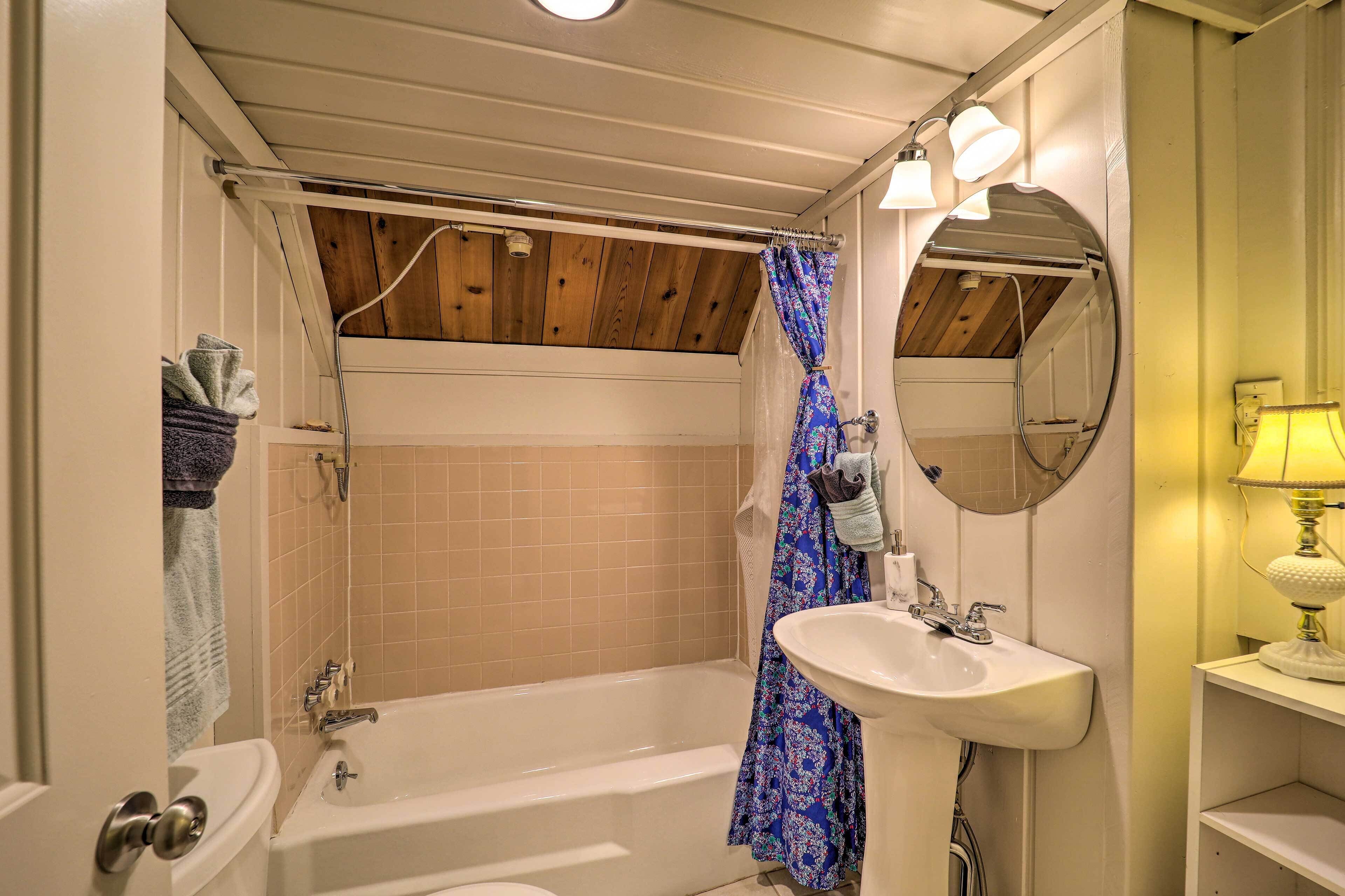 A bathroom with a bathtub, a sink, a mirror, and a shower curtain.