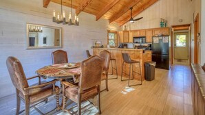 A wooden interior with a dining table and chairs, a kitchen area with wooden cabinets, and a hanging light fixture. - Pagosa Lakefront Home w/ Hot Tub, A/c, & Canoe! (Pagosa Springs)