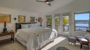 A bedroom with a large bed, a ceiling fan, and a view of a lake through the windows. - Pagosa Lakefront Home w/ Hot Tub, A/c, & Canoe! (Pagosa Springs)