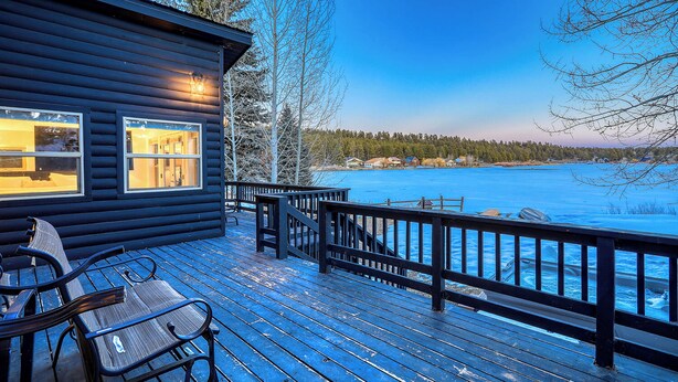 A wooden deck with chairs, a railing, and a view of a frozen lake. - Pagosa Lakefront Home w/ Hot Tub, A/c, & Canoe! (Pagosa Springs)