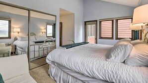 A hotel room with a large bed, a desk, a chair, and a mirror. - Mtn View Granby Condo w/ In-unit Hot Tub! (Granby)