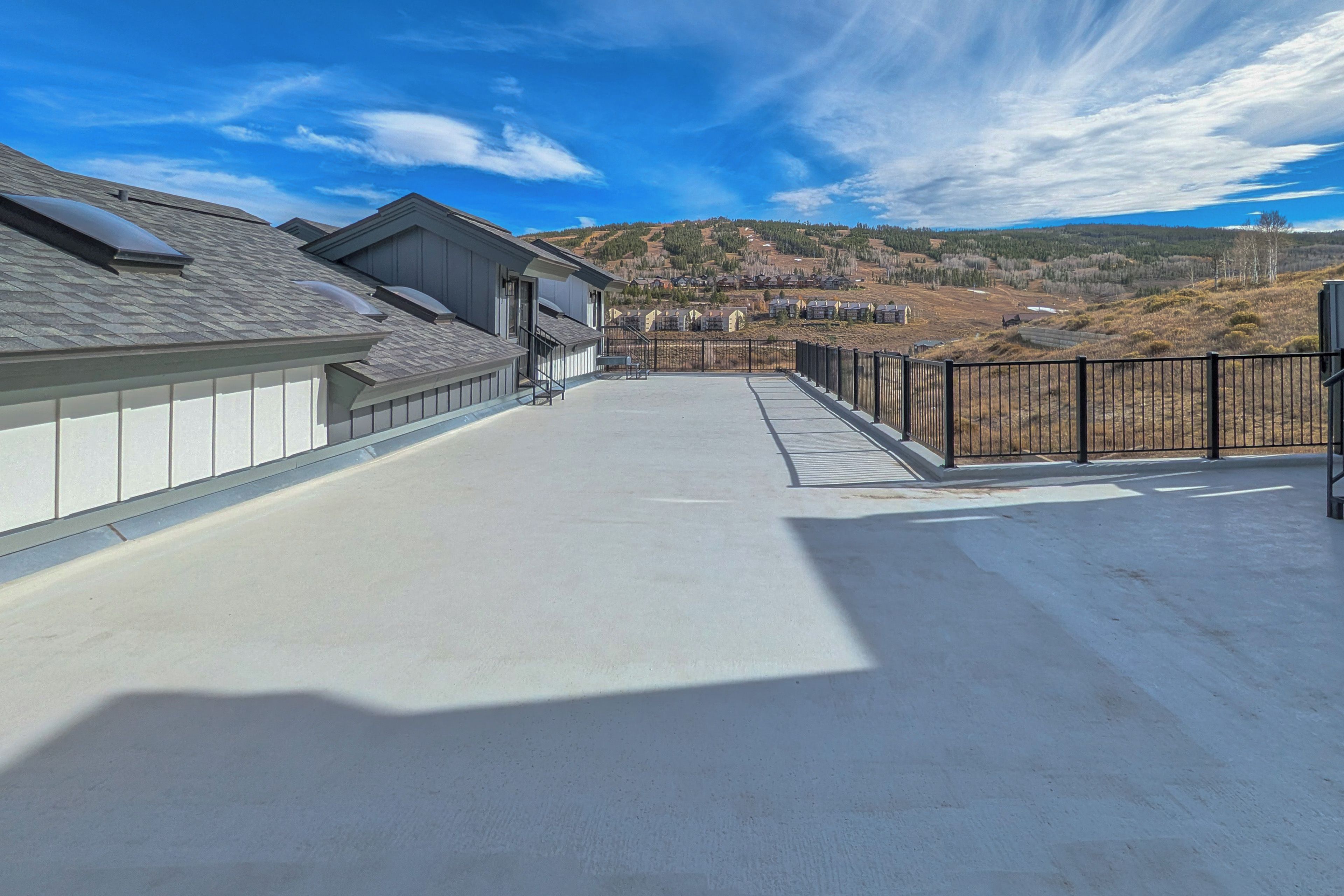 Una terraza en la azotea con vistas a una zona residencial y colinas.