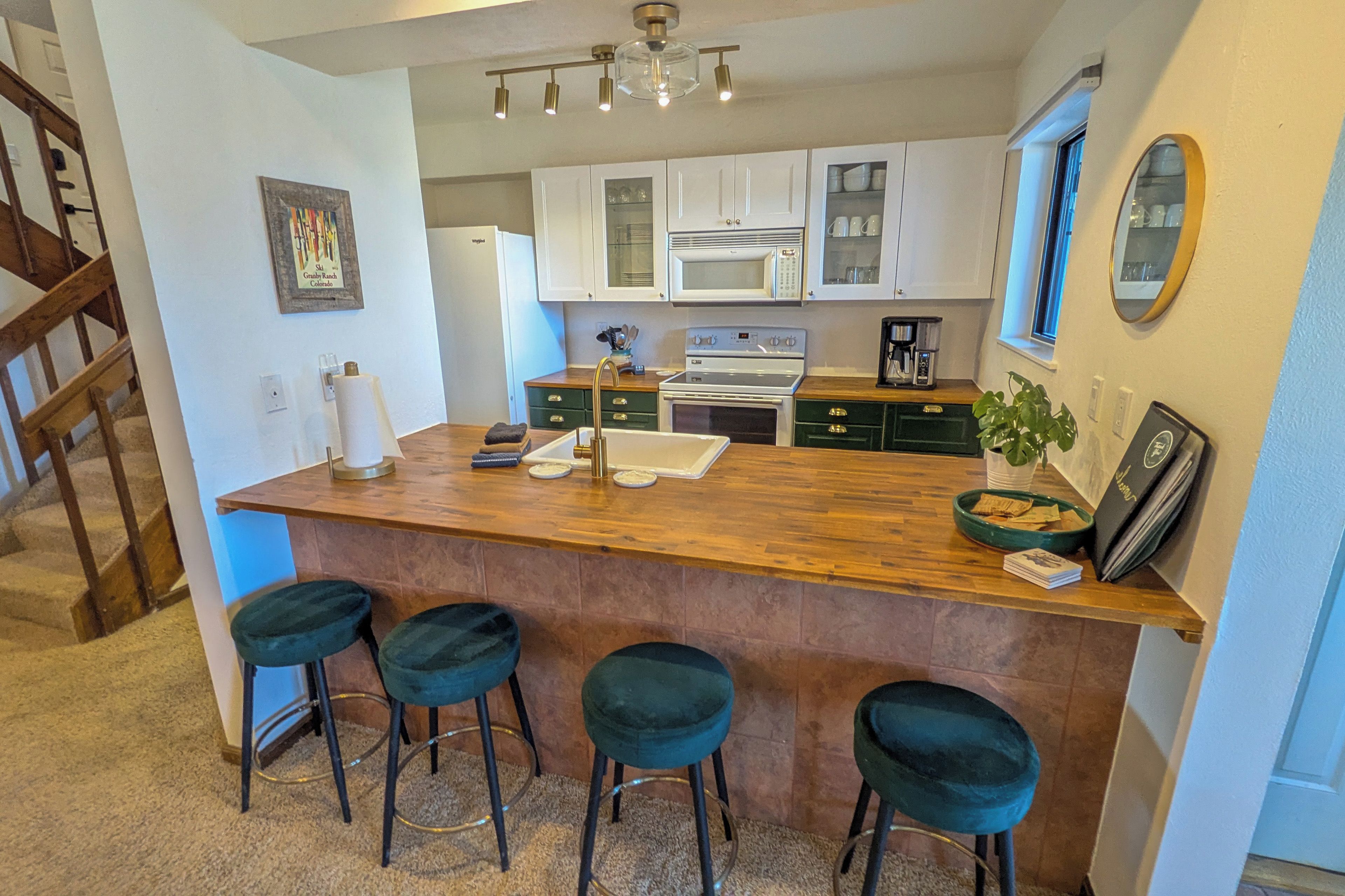 Une cuisine avec un îlot central en bois, des tabourets de bar, une cuisinière et des armoires blanches.