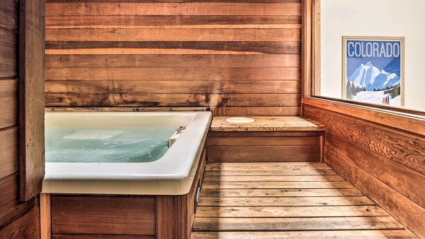 A wooden cabin interior with a hot tub, wooden walls, and a poster of Colorado. - Mtn View Granby Condo w/ In-unit Hot Tub! (Granby)