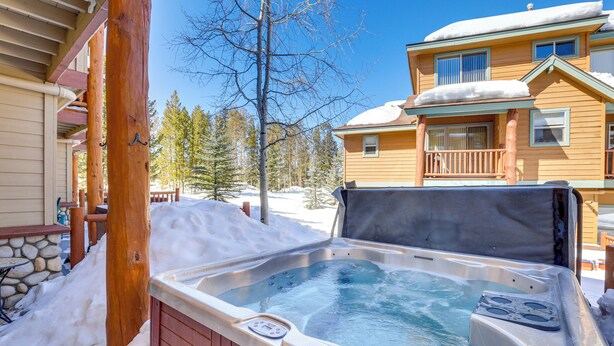 A hot tub with a control panel, surrounded by snow, with a wooden deck and a stone wall in the background. - Airy Winter Park Gem w/ Private Outdoor Hot Tub! (Winter Park)