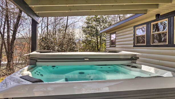Un bain à remous dans un espace extérieur abrité, avec une maison en arrière-plan.