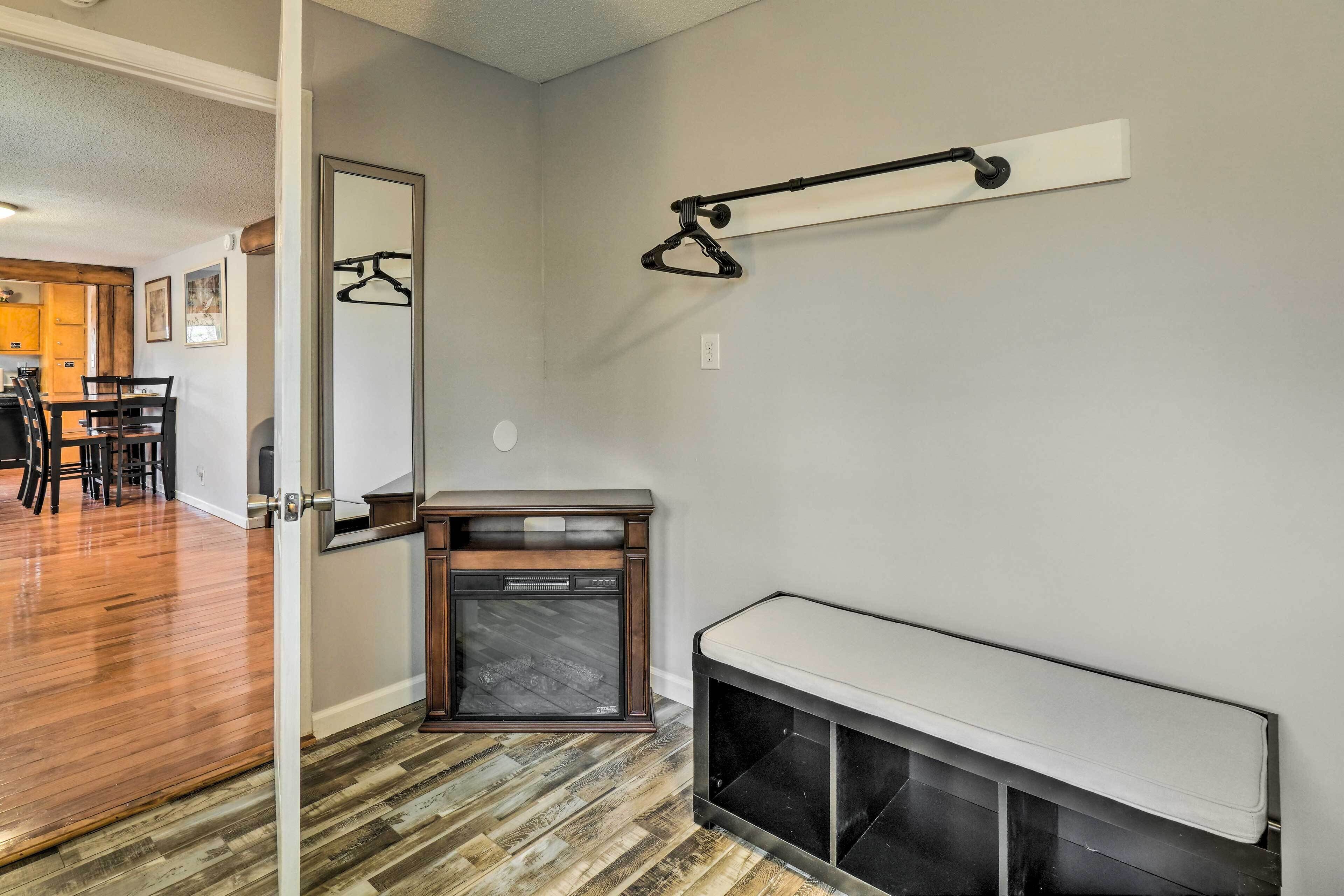 A modern interior with a wooden floor, a dining area with chairs, a bench, and a coat rack.