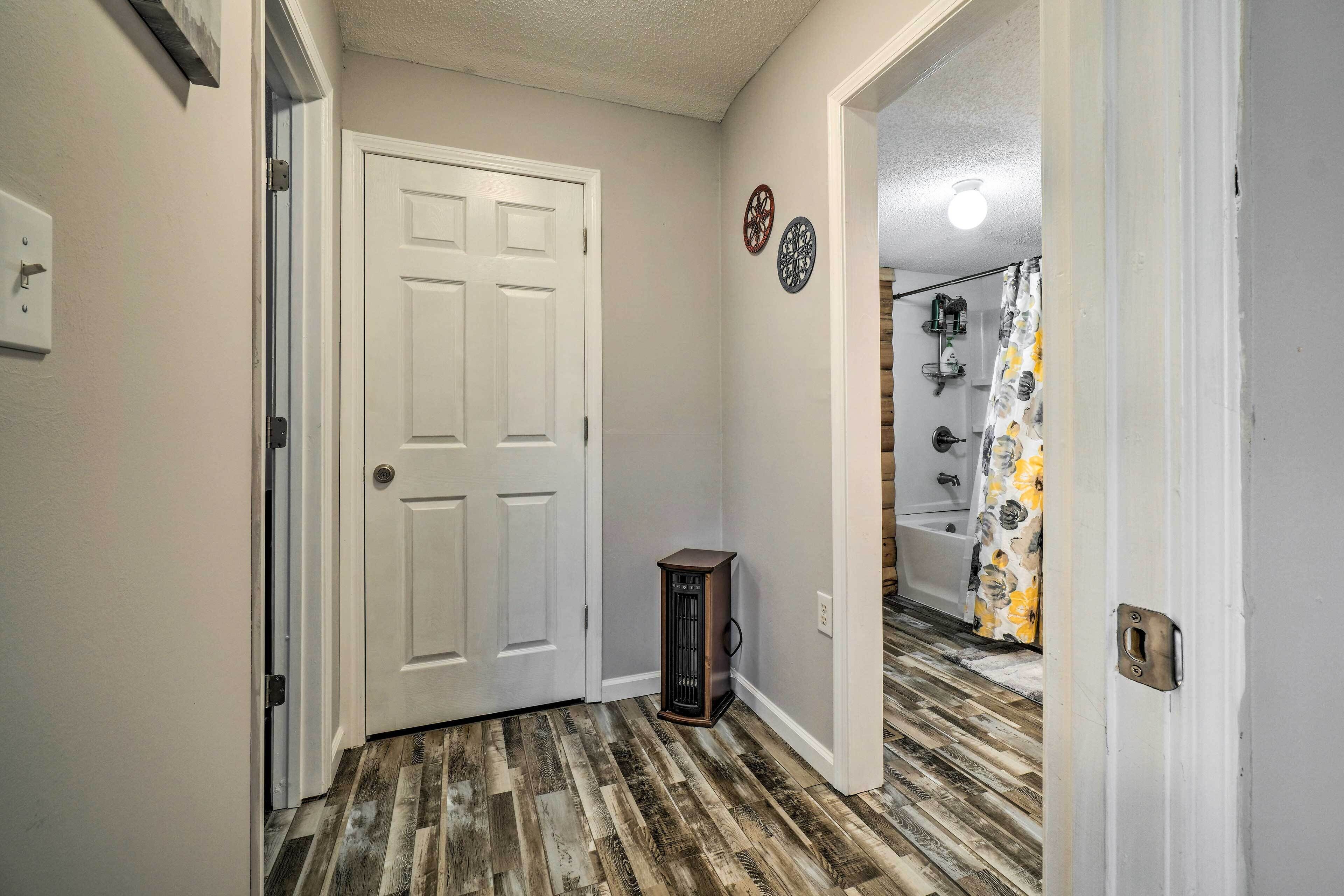 A hallway with a wooden floor, a white door, and a small table.