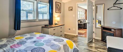 Quarto com cama, penteadeira e janela com cortinas.