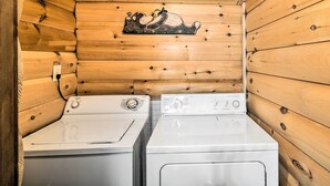 Une petite buanderie équipée de deux machines à laver blanches et d’un mur en bois orné d’un motif décoratif.
