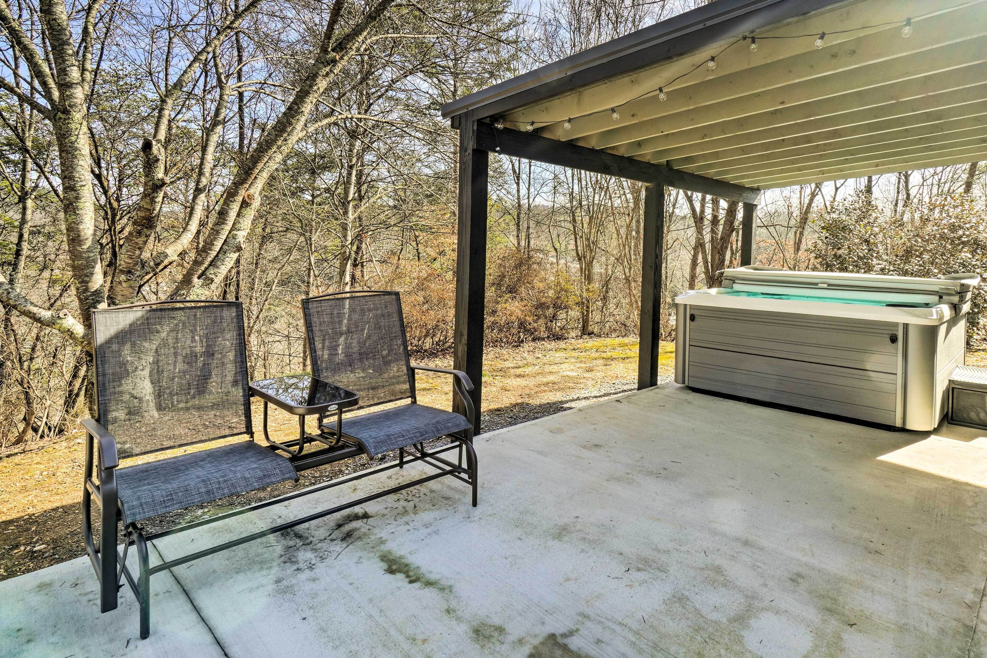 An outdoor patio with two metal chairs and a built-in hot tub.