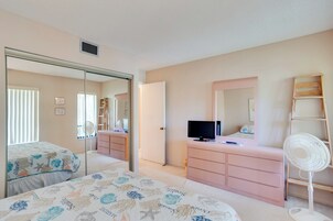 Un dormitorio con cama, cómoda, espejo, televisor y ventilador.