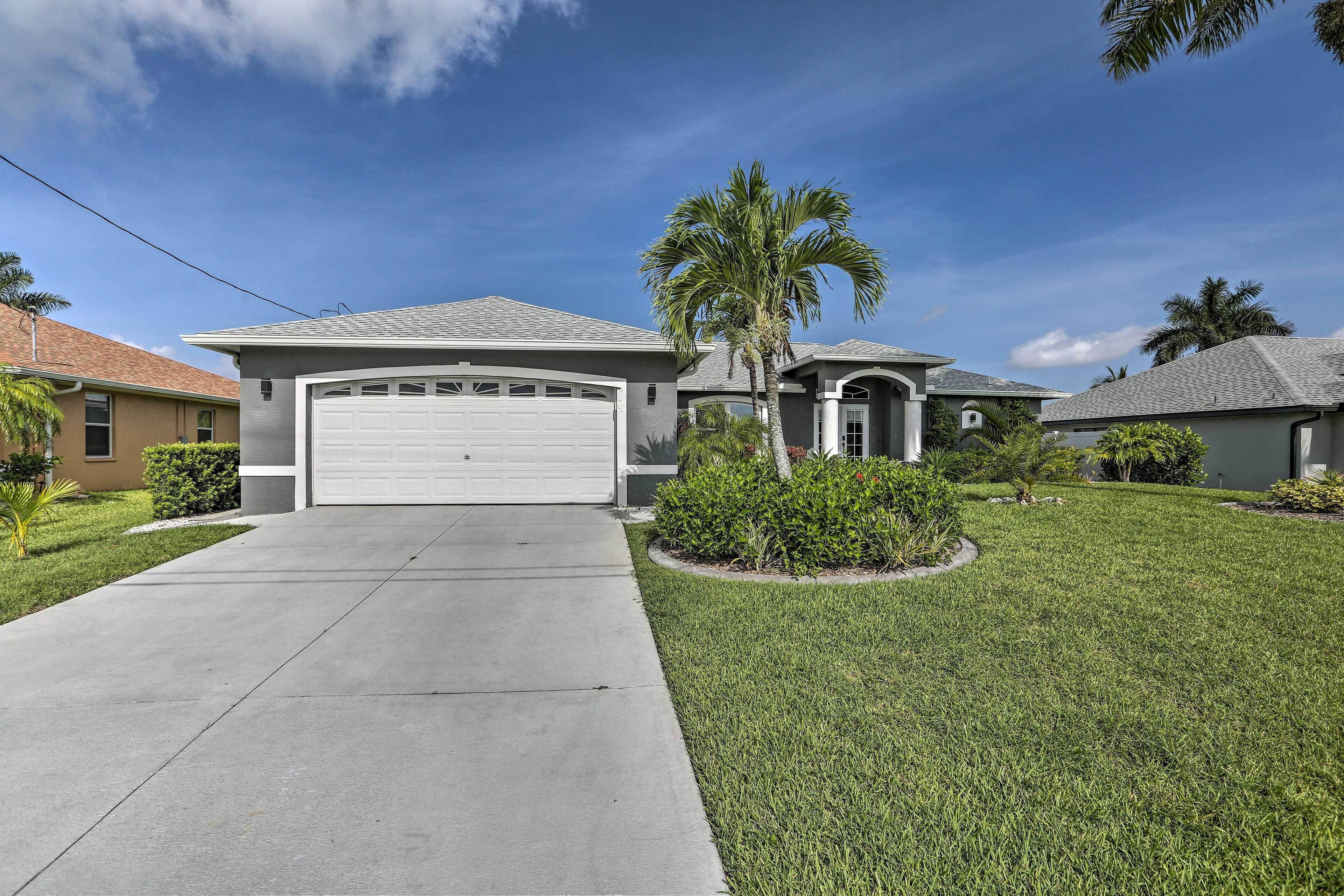 A residential house with a garage, a well-maintained lawn, and a palm tree.