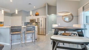 A modern kitchen with stainless steel appliances, a central island with bar stools, and pendant lighting. - Private Pool & Canal Views: Home in Cape Coral (Cape Coral)
