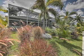 A modern building with a glass facade surrounded by tropical plants and palm trees.