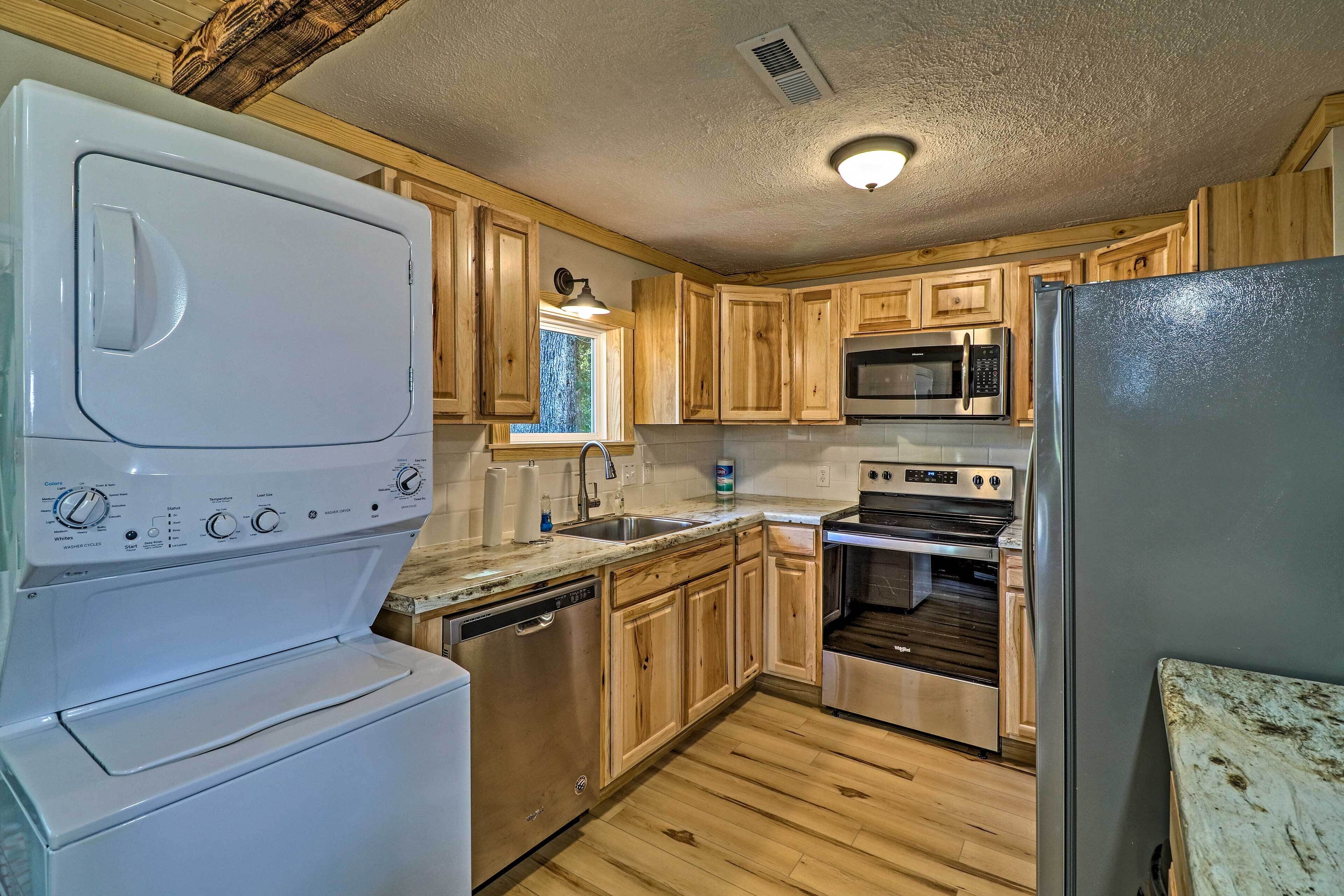 A compact kitchen with wooden cabinets, a stainless steel refrigerator, a dishwasher, a microwave, and an oven.