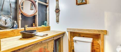 A rustic bathroom with a wooden vanity, a white toilet, and a mirror.