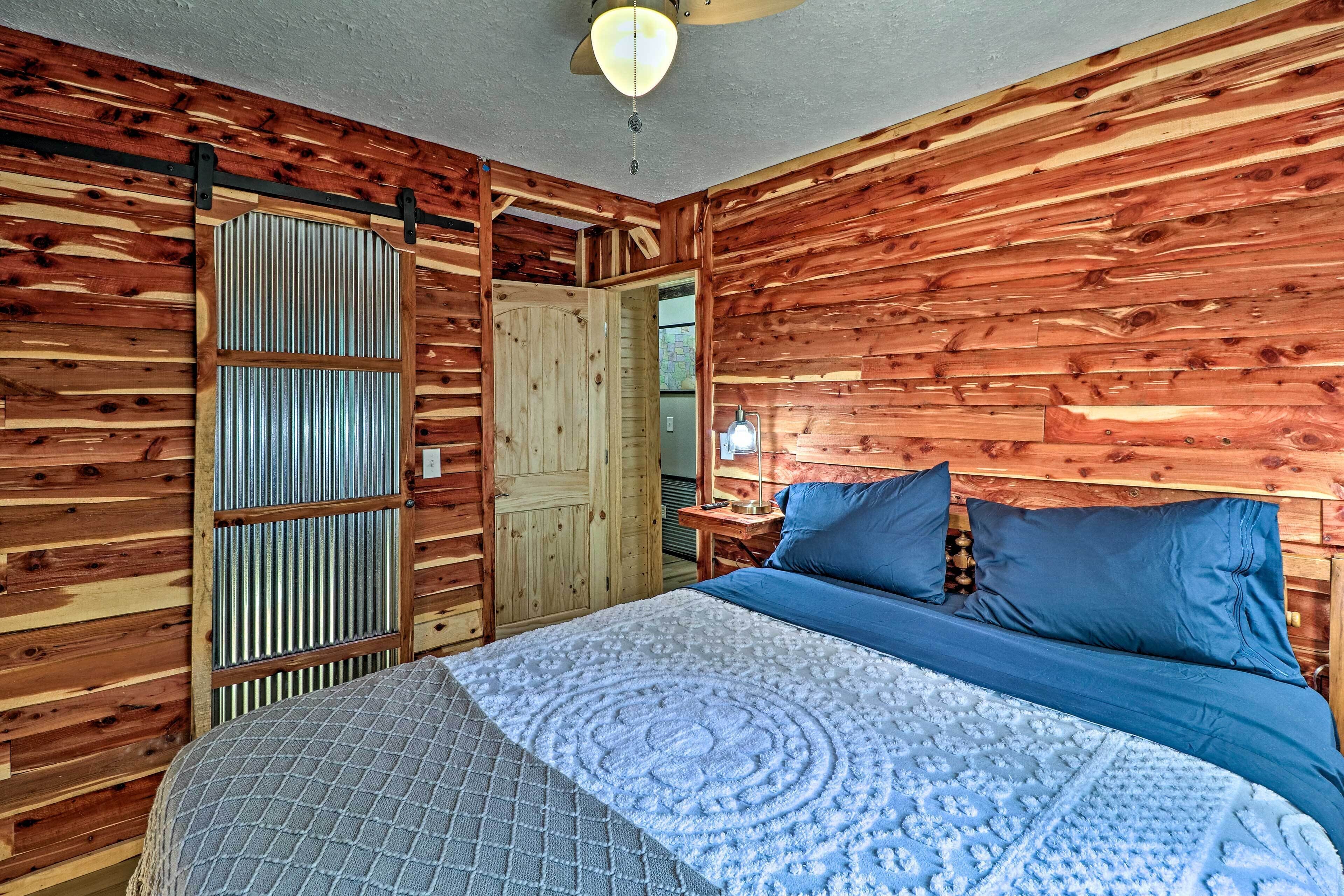 Ein Zimmer mit Holzboden, einem Bett, einem Nachttisch und einer Tür.
