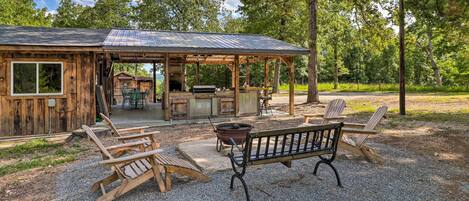 A rustic cabin with a covered patio, outdoor seating, and a barbecue area.