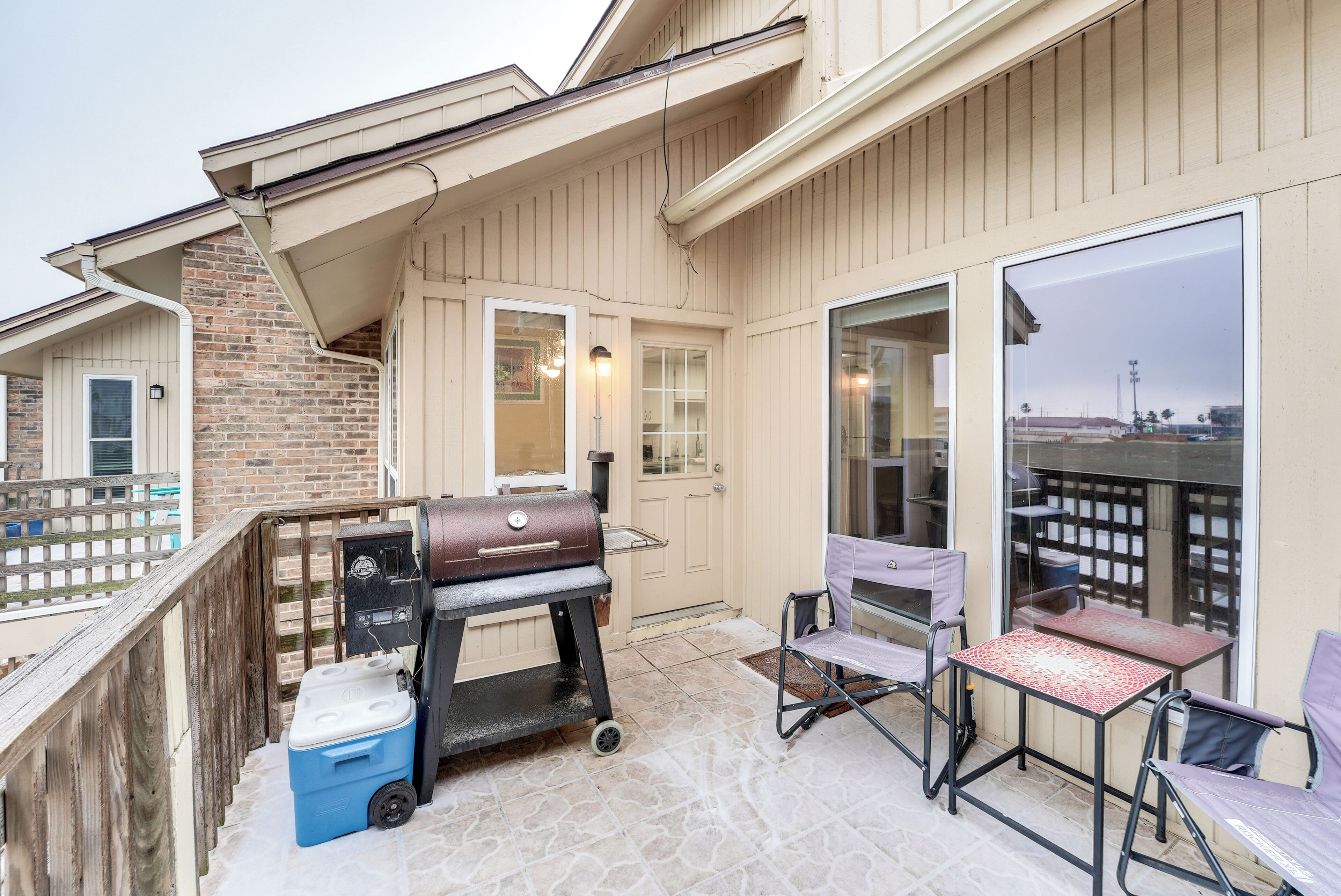 A patio with a grill, a table, and chairs.
