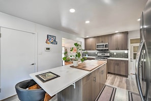 A modern kitchen with wooden cabinets, stainless steel appliances, and a central island with a plant. - < 7 Mi to Dtwn: Denver Home w/ Large Yard! (Denver)