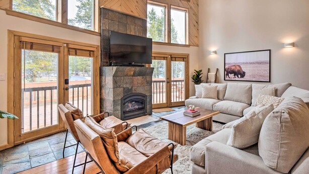 A spacious living room with a stone fireplace, large windows, and a comfortable seating area. - 2 Mi to Dtwn: Leadville Haven w/ 2 Furnished Decks (Leadville)