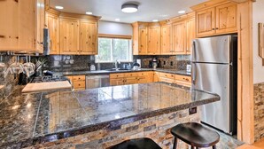 A kitchen with wooden cabinets, granite countertops, a stainless steel refrigerator, and a large island with stools. - 2 Mi to Dtwn: Leadville Haven w/ 2 Furnished Decks (Leadville)