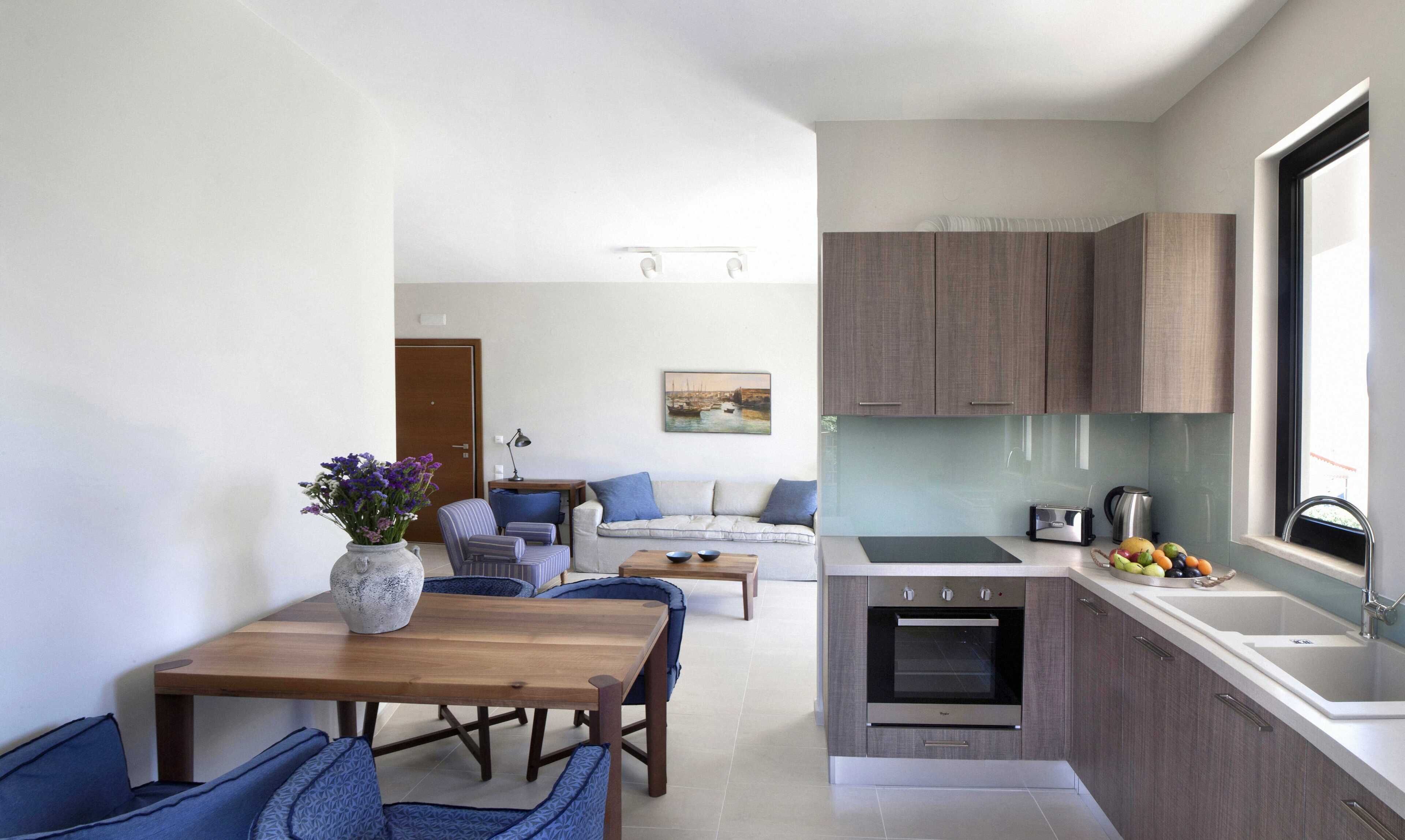 Un espacio habitable compacto con comedor, sofá, kitchenette y vistas al exterior.
