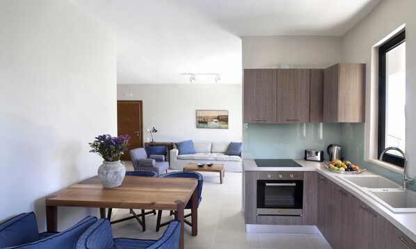 A compact living space with a dining area, sofa, kitchenette, and a view of the outdoors.