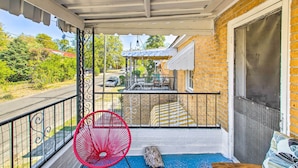 Un balcon avec une chaise rouge, un banc en bois et un bloc de pierre.