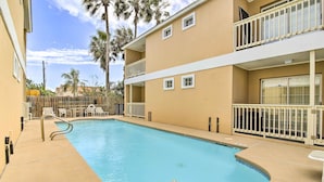 A swimming pool with a no diving sign, surrounded by a beige building with balconies and a wooden fence. - South Padre Island Getaway - Newly Renovated! (South Padre Island)