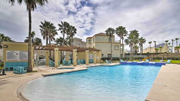 A swimming pool with lounge chairs and palm trees. - Sunny SPI Las Villas Condo w/ Resort Amenities! (South Padre Island)