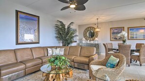 A living room with a brown leather sofa, a glass coffee table with a wooden base, wicker chairs, and a large mirror on the wall. - Sunny SPI Las Villas Condo w/ Resort Amenities! (South Padre Island)