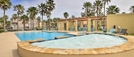 A swimming pool with lounge chairs and palm trees.