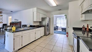 A modern kitchen with white cabinets, a stainless steel refrigerator, and a black countertop. - Sunny Abode, 10 Mi to University of Florida! (Gainesville)