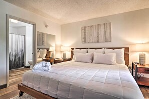 Une chambre à coucher avec un grand lit, des lampes de chevet, un miroir et un tableau au mur.