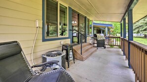 A covered porch with a grill, outdoor seating, and a staircase leading to a covered entryway.