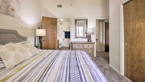 A bedroom with a bed, a dresser, a mirror, and a ceiling fan.