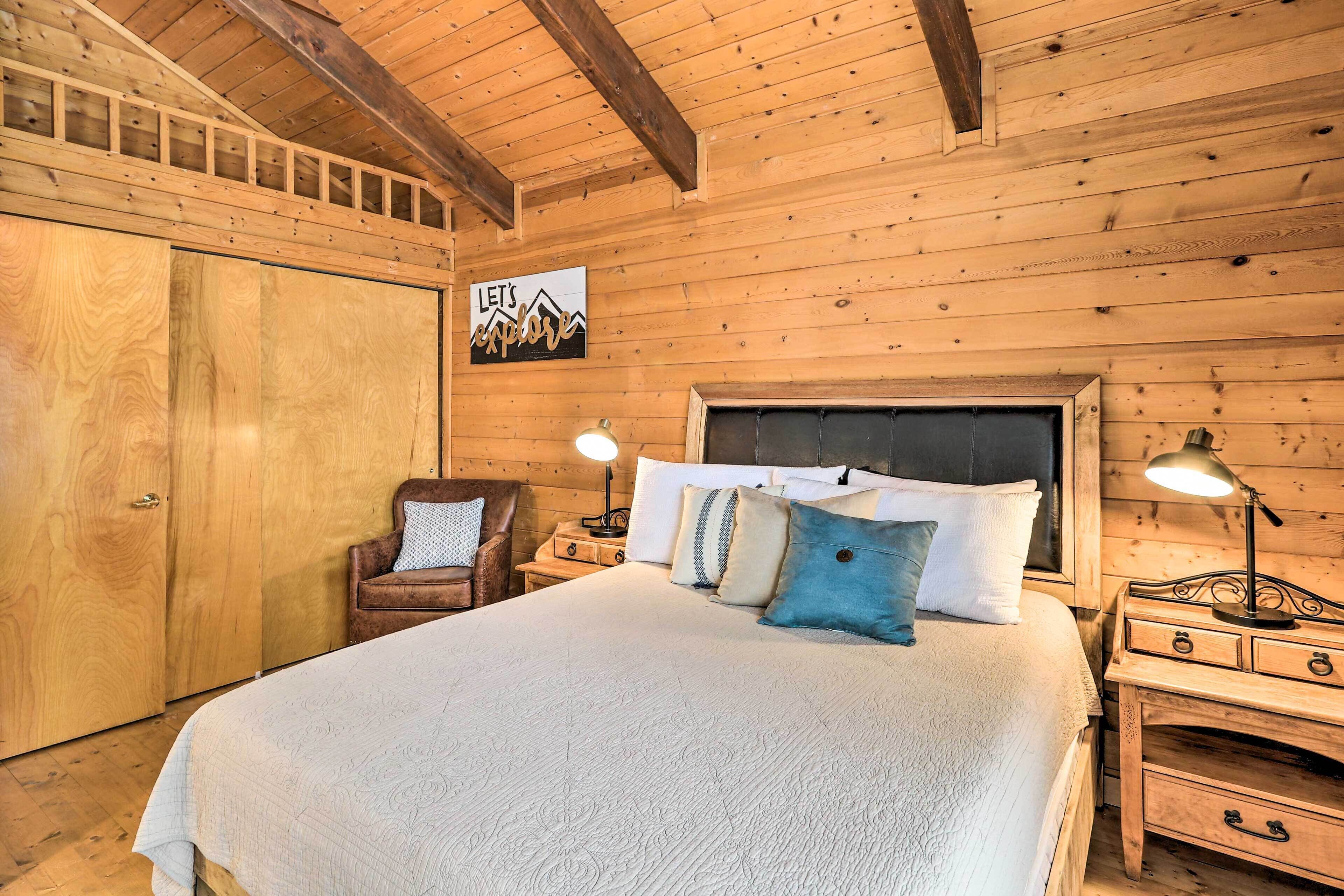 A wooden room with a bed, nightstands, a chair, and a wardrobe.