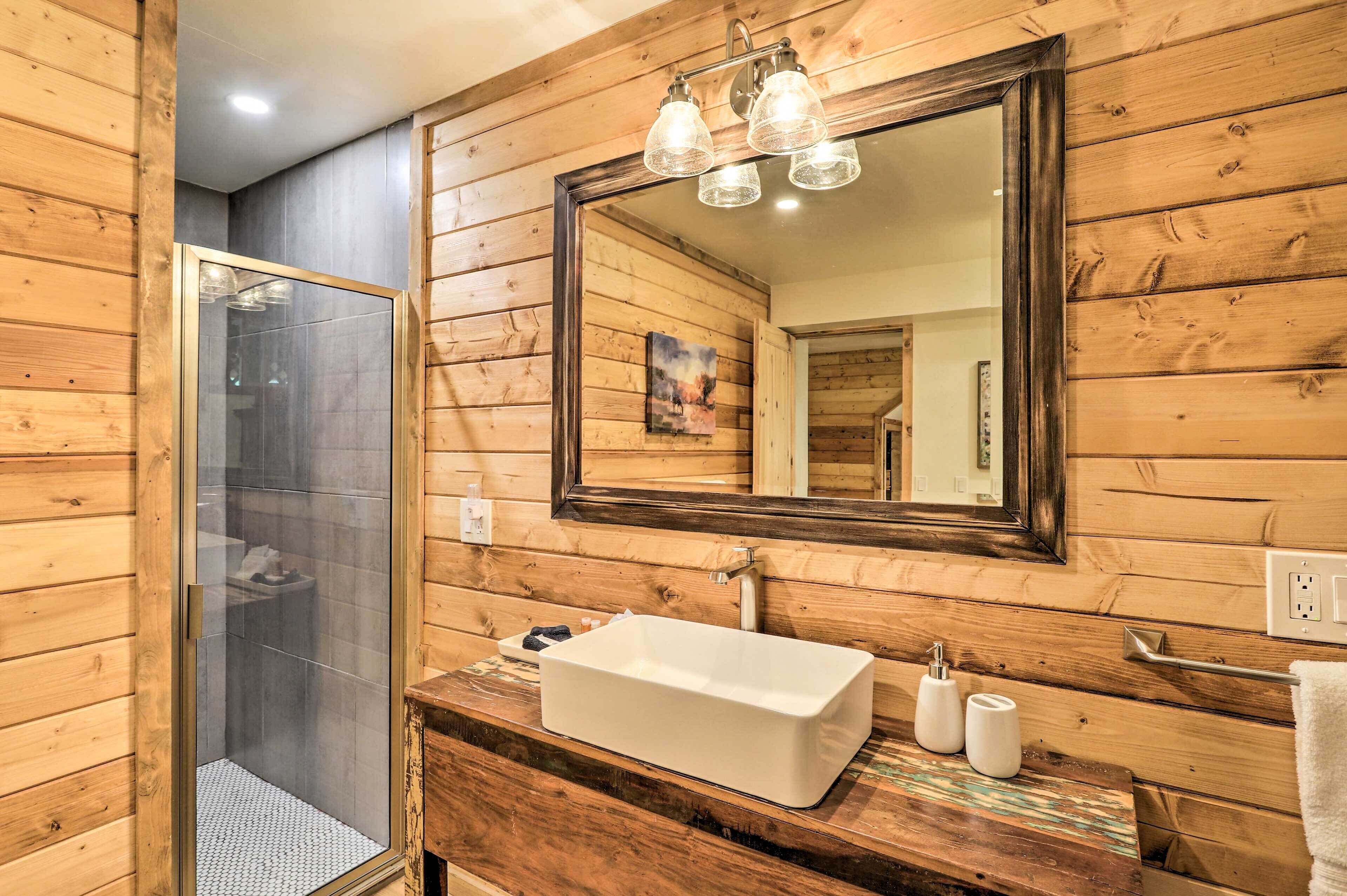 A wooden-paneled bathroom with a glass-enclosed shower, a white sink, and a large mirror above the sink.