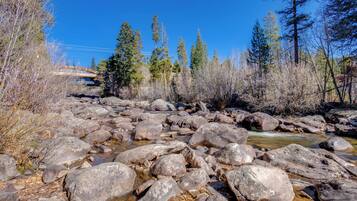 A rocky stream with large boulders and trees in the background.