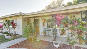 A house with a patio area featuring a table and chairs, surrounded by various plants and a small garden. - Charming Home w/ Yard ~ 5 Mi to Clearwater Beach! (Clearwater)