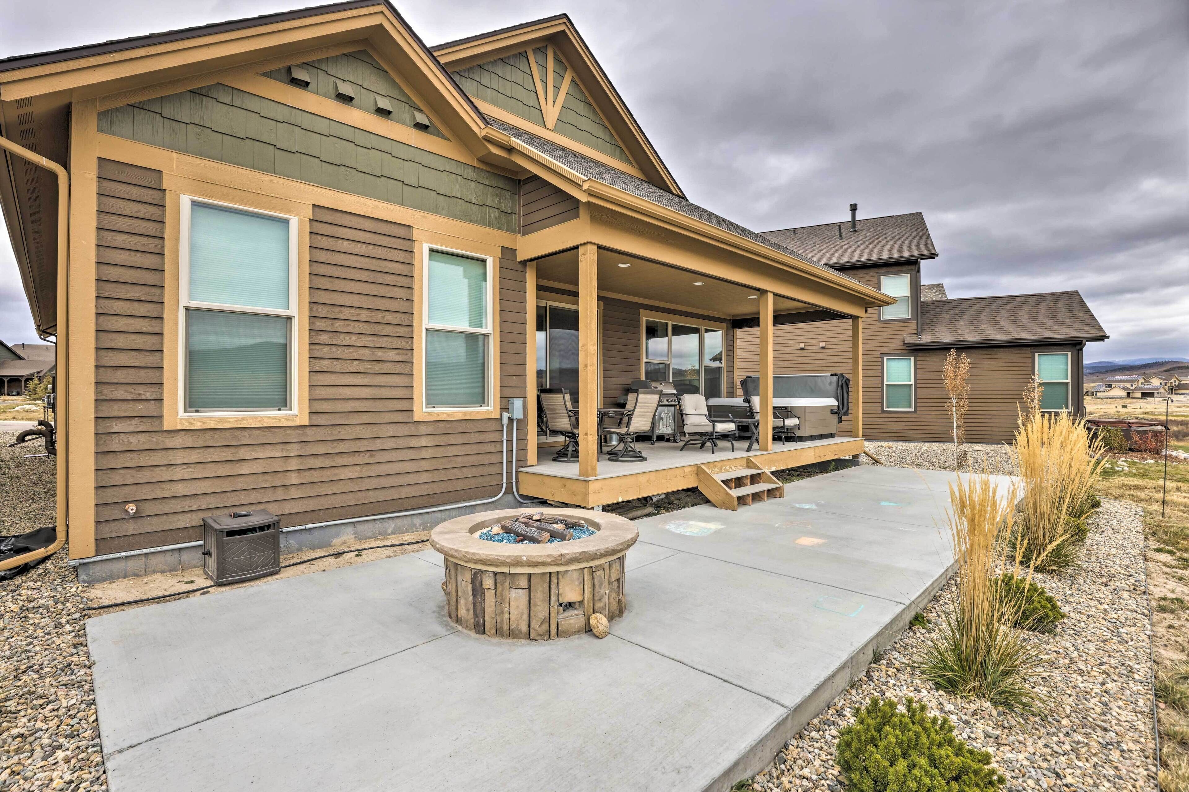 A two-story house with a covered patio, a fire pit, and a landscaped garden.