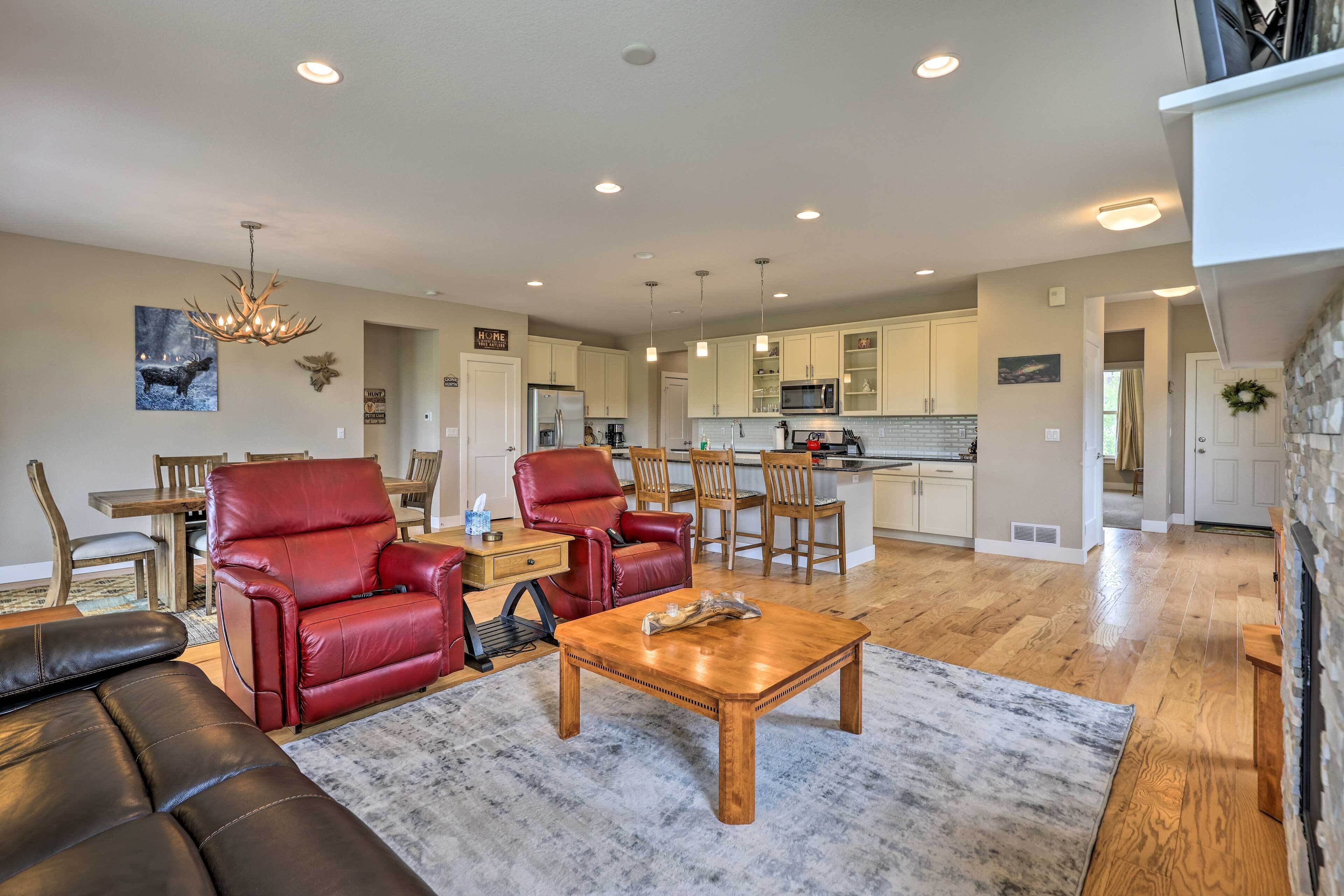 A spacious living room with a fireplace, leather sofas, and a dining area with wooden chairs.