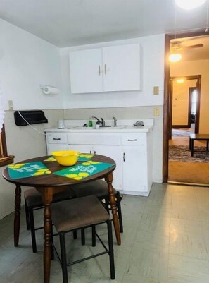 Compact kitchen area with a dining table and chairs, sink, and faucet.