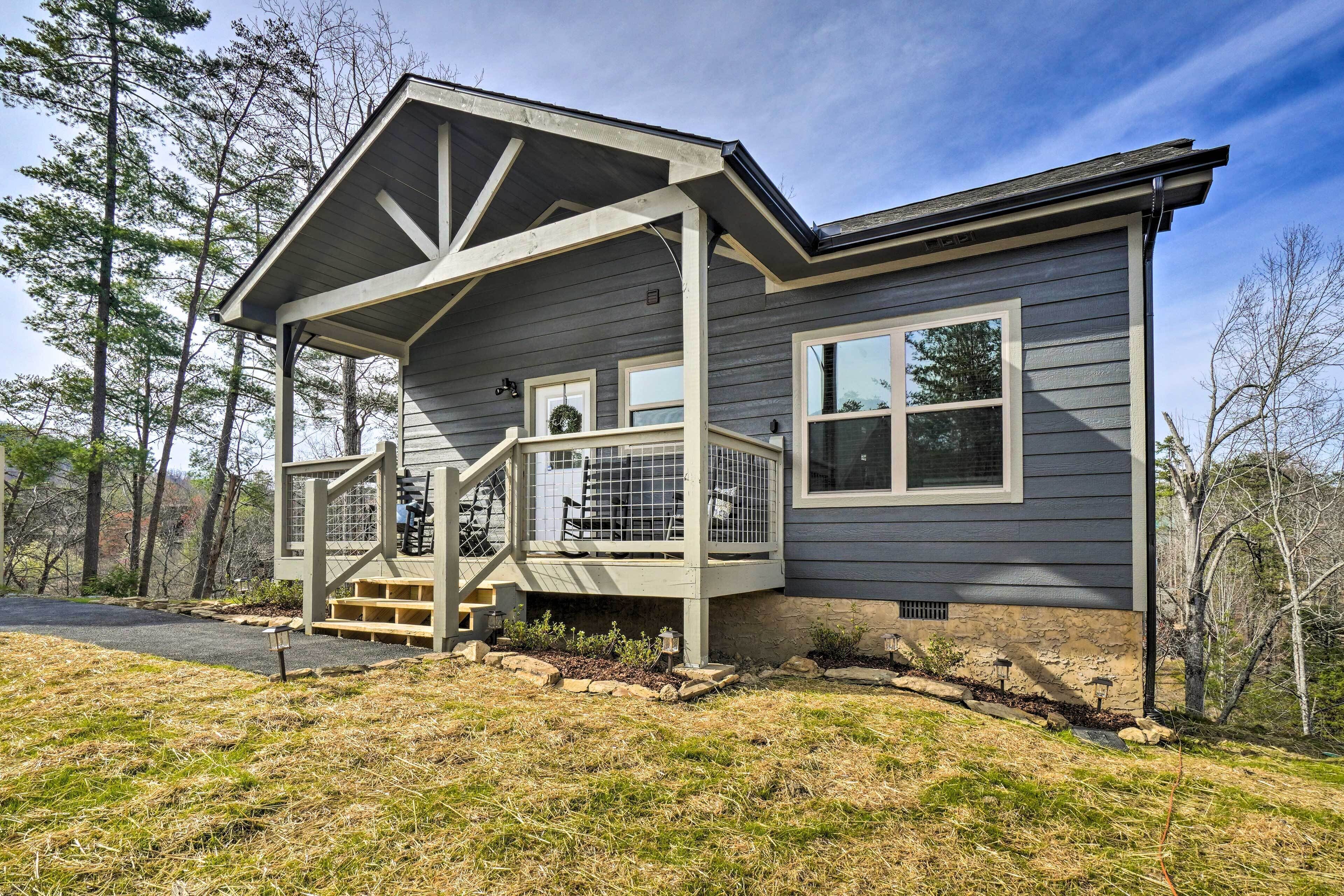 A two-story house with a covered porch and a stone foundation.