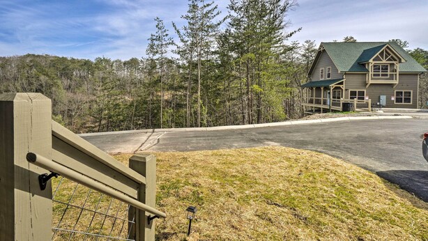 Ein Chalet mit überdachter Terrasse, befestigter Auffahrt und bewaldeter Umgebung.