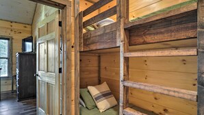 Ein Holzblockhaus-Interieur mit einem Stockbett, einer Tür und einem Fenster.